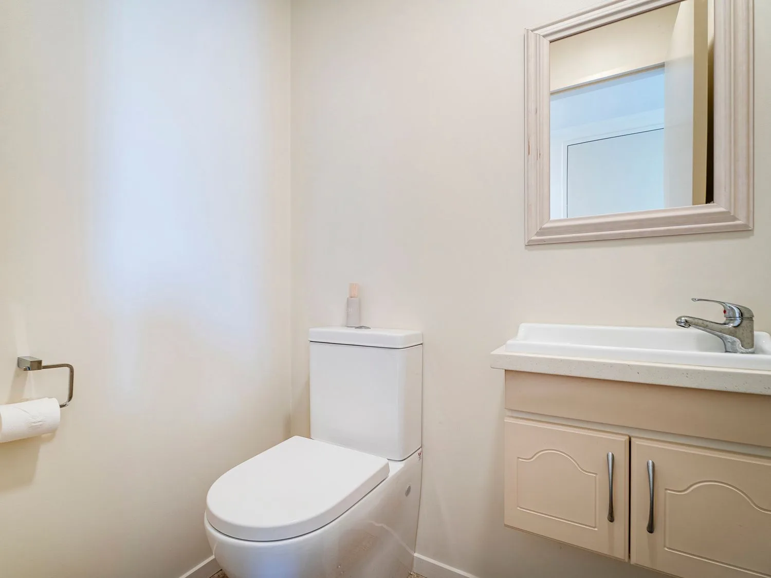 Un baño con un inodoro, un lavabo y un espejo de pared.