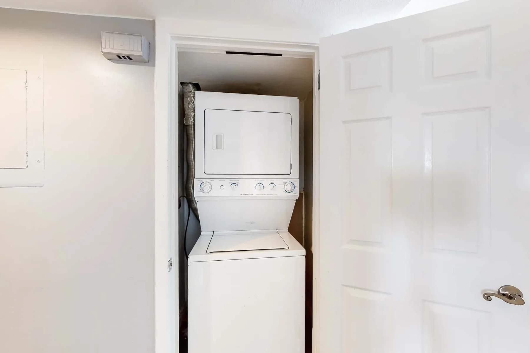 A stacked washer and dryer sit in a small laundry closet.