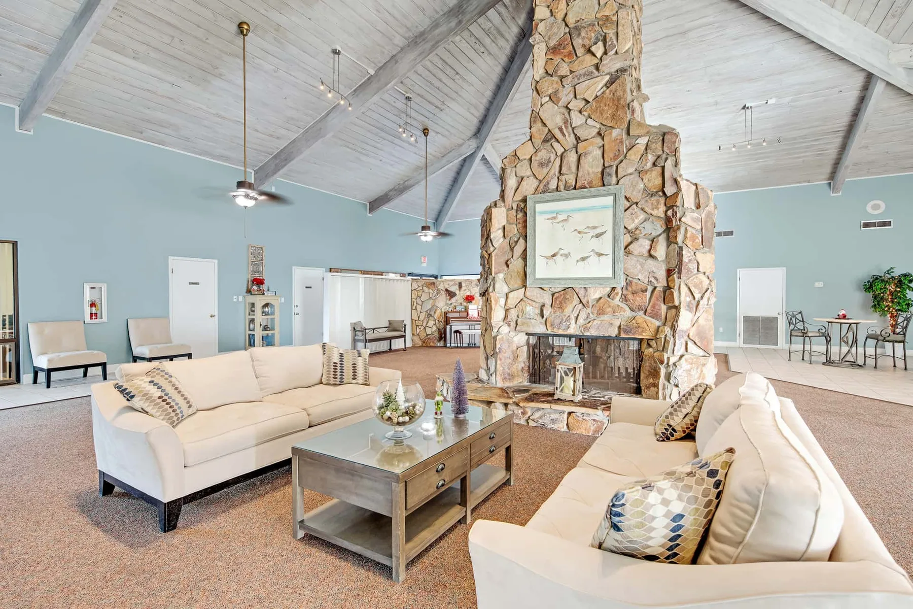 A spacious lounge with light seating around a central stone fireplace.