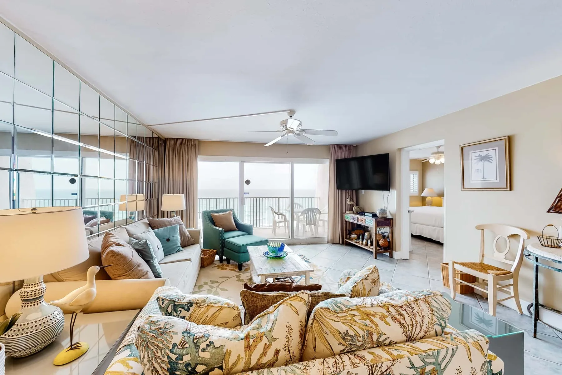 A bright living room with seating arranged around a coffee table and a television.