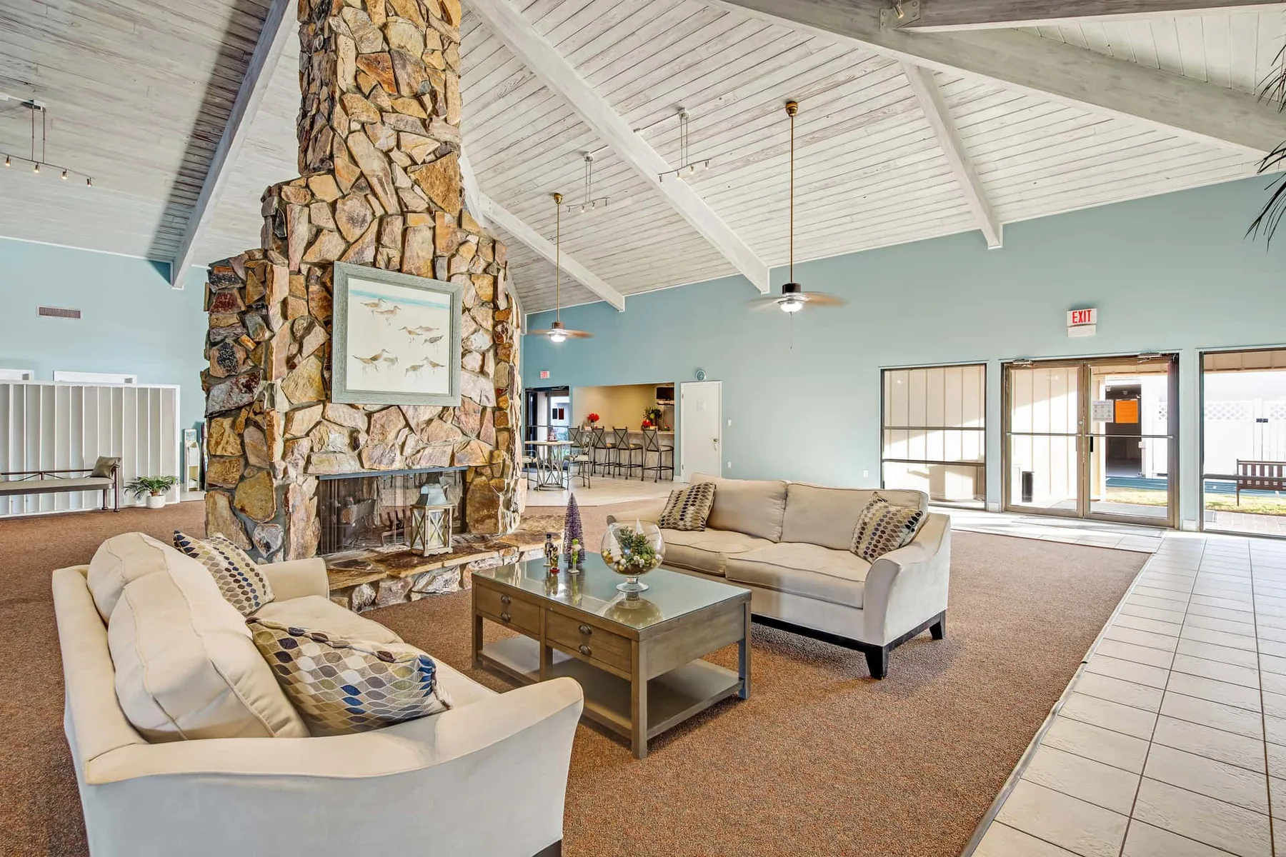 A spacious lounge with seating arranged around a large stone fireplace.