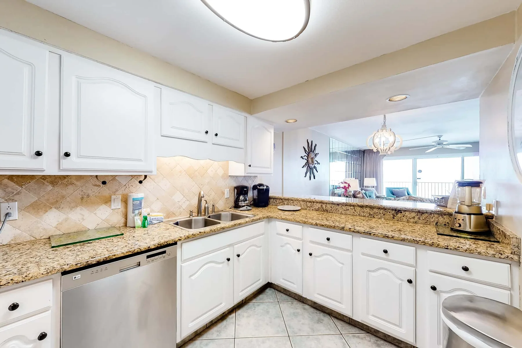 A bright kitchen with white cabinets and a countertop overlooking the living area.