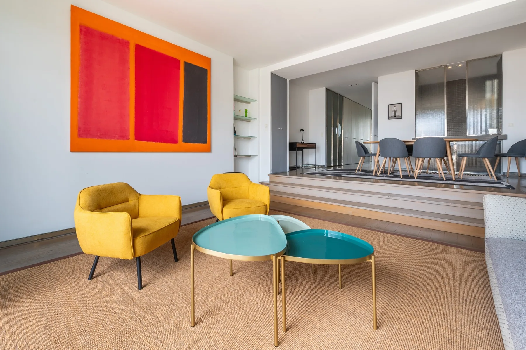 A living area with yellow seating and two turquoise coffee tables.