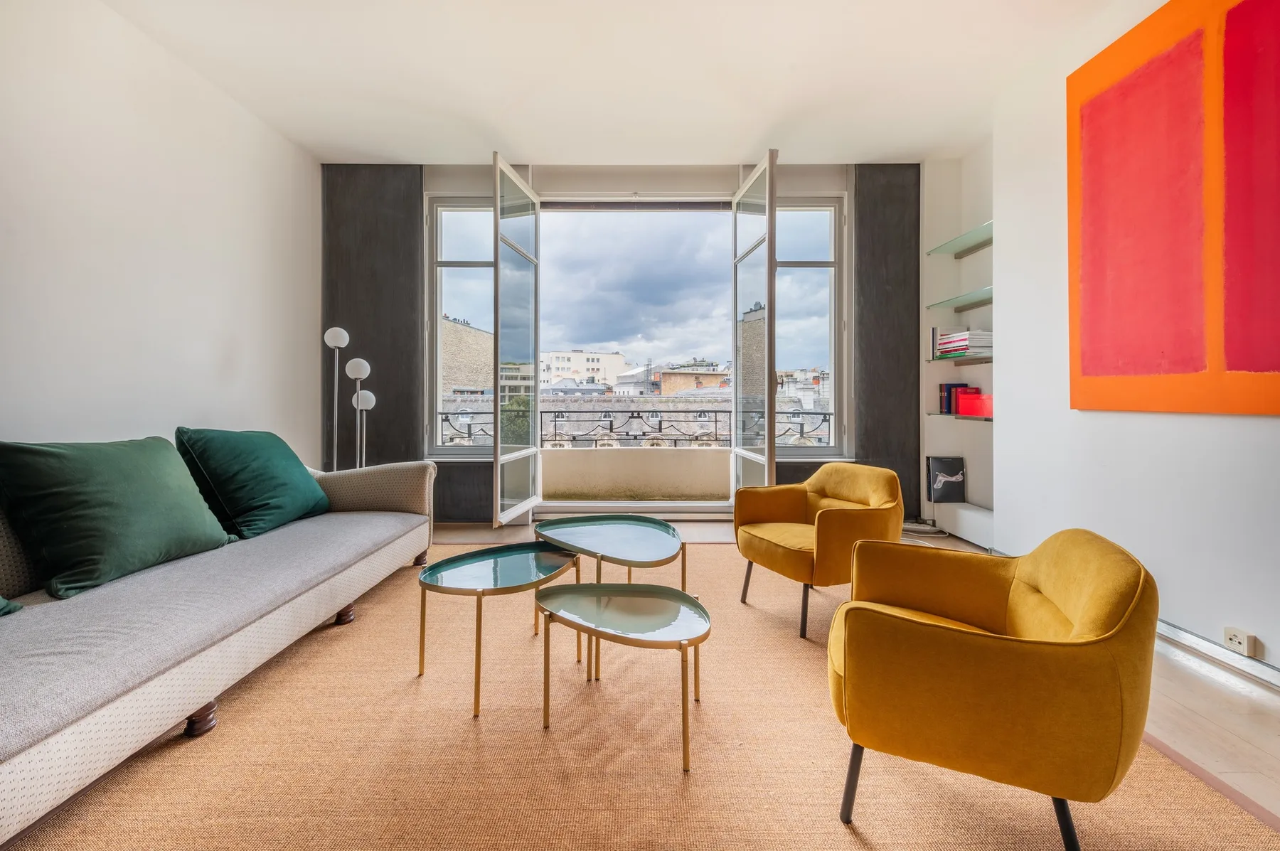 A living room with seating and open windows overlooking the city.