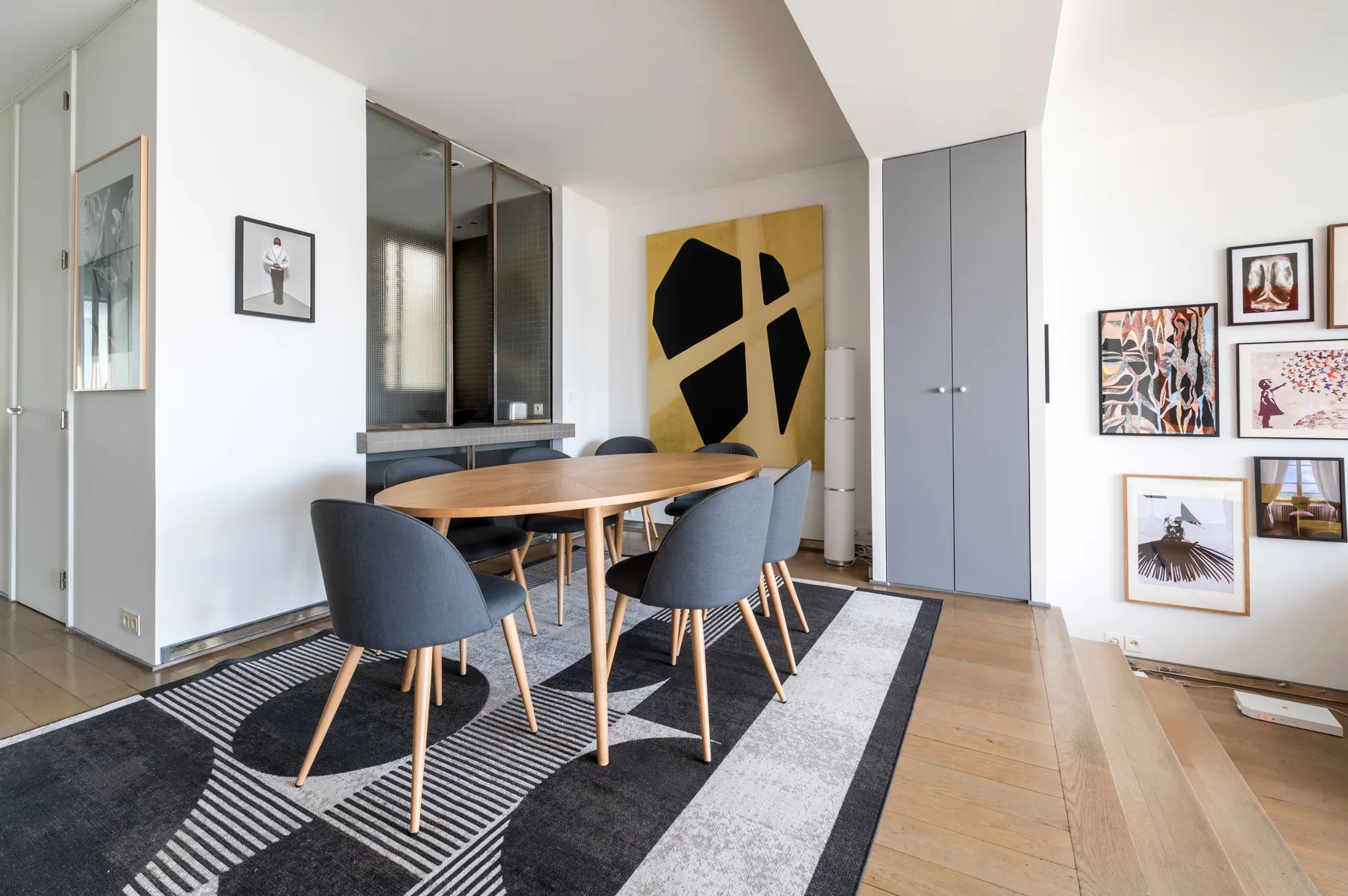 A dining area with a wooden table and chairs on a patterned rug.