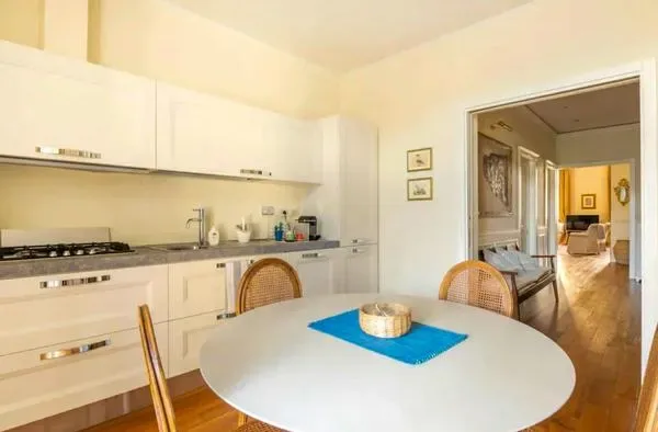 Una cocina luminosa con gabinetes blancos y una mesa redonda.