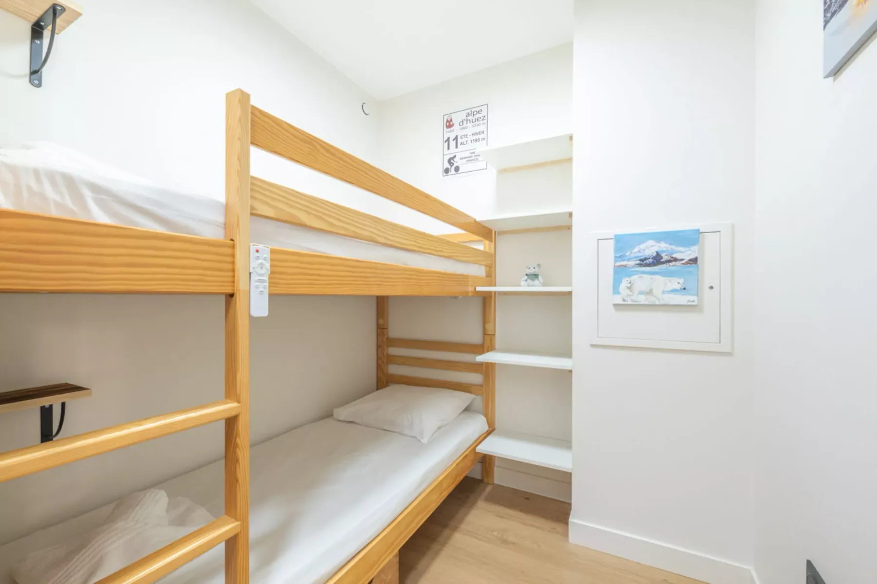 A compact bedroom features wooden bunk beds and built-in shelving.