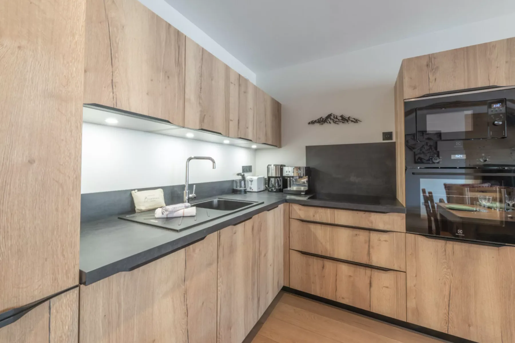 A modern kitchen with light wood cabinets, a countertop, and built-in appliances.