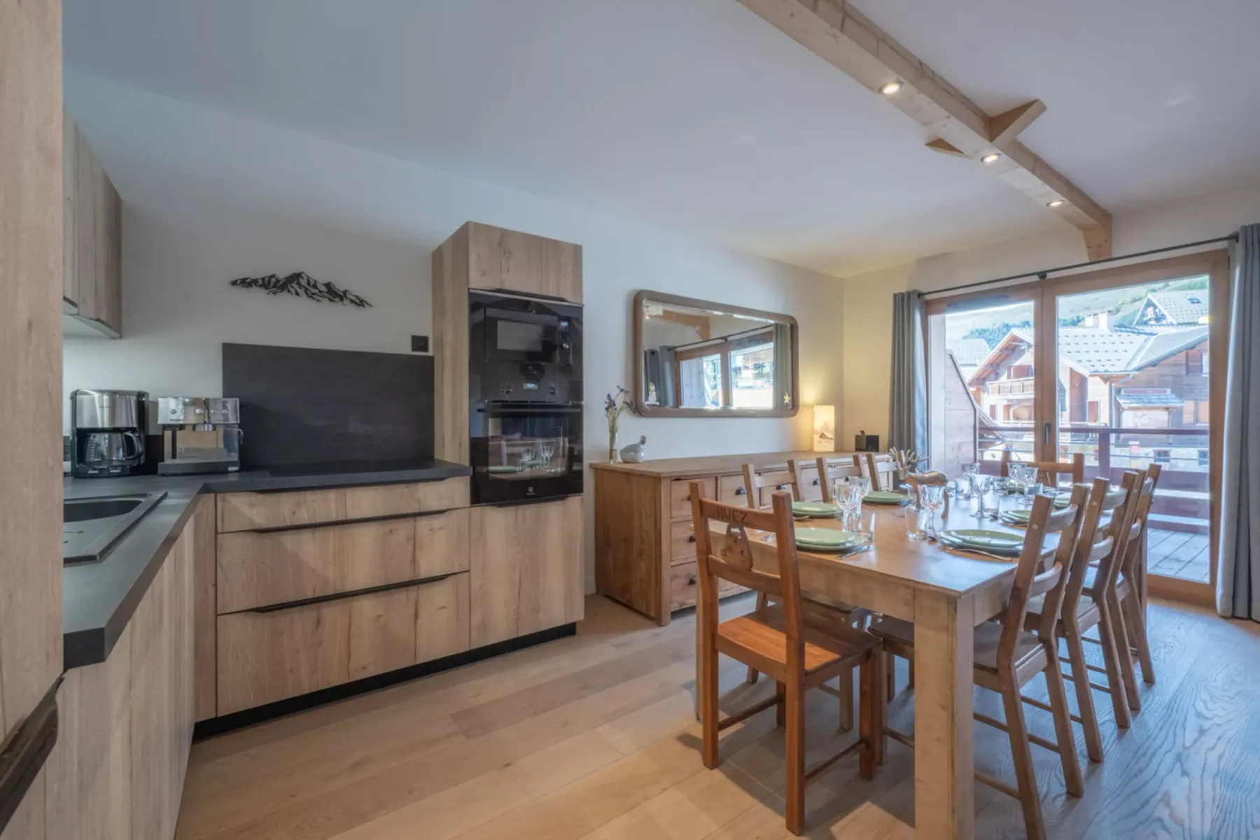 A dining area with a wooden table and chairs beside a kitchen.