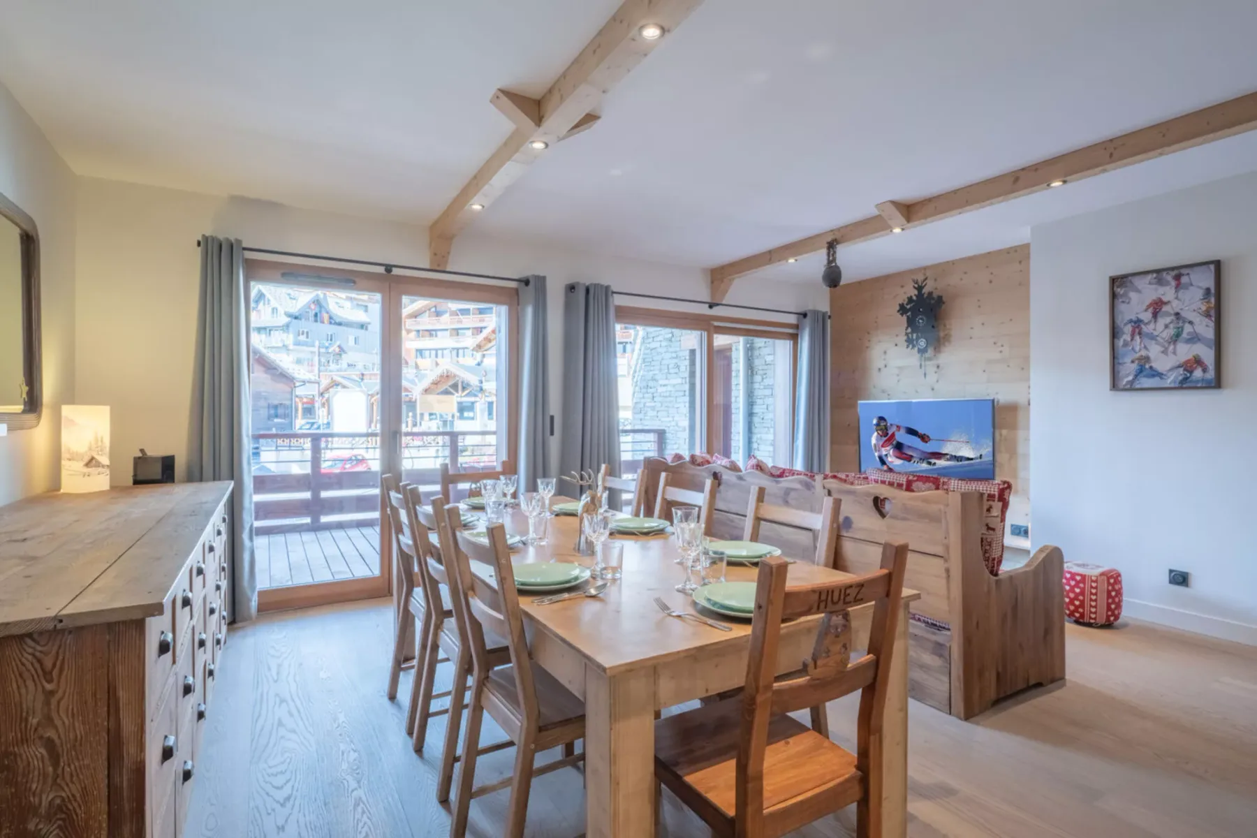 A dining area with a long wooden table and sliding glass doors opening onto a balcony.