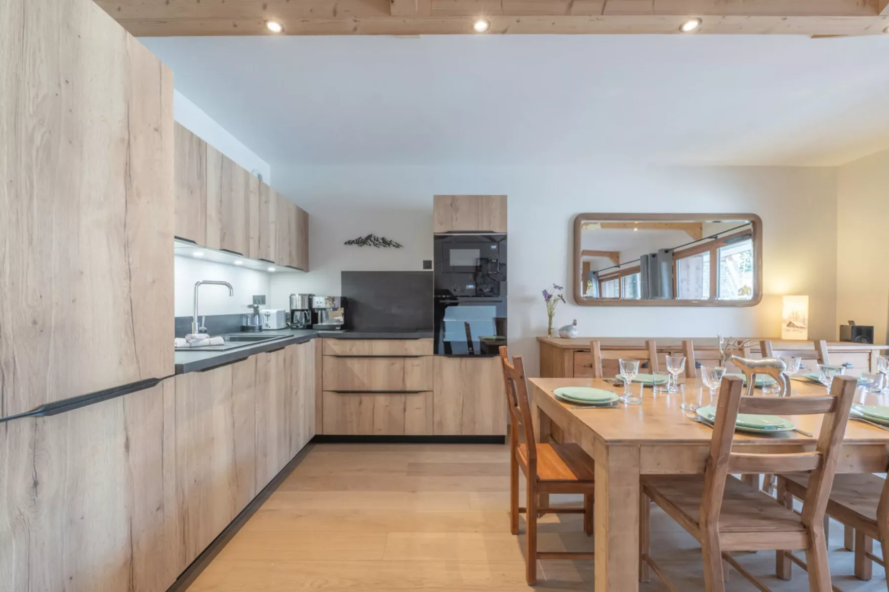 A kitchen and dining area with light wood cabinetry and a set table.