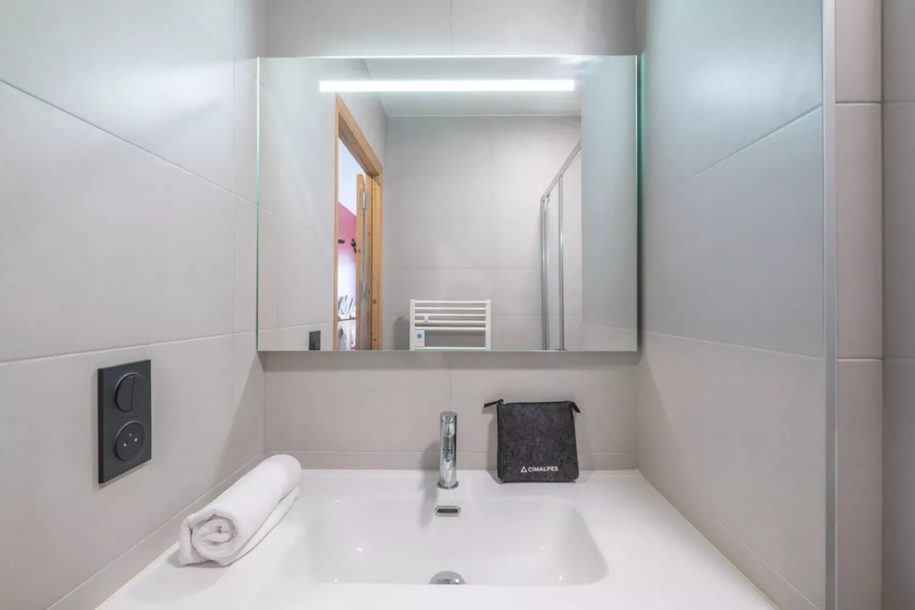 A bathroom vanity with a sink, faucet, and illuminated mirror.