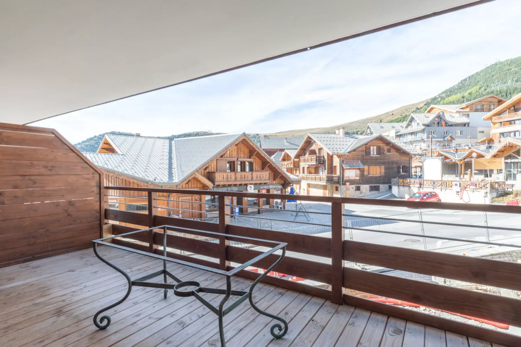 A wooden balcony overlooks a cluster of chalet-style buildings.
