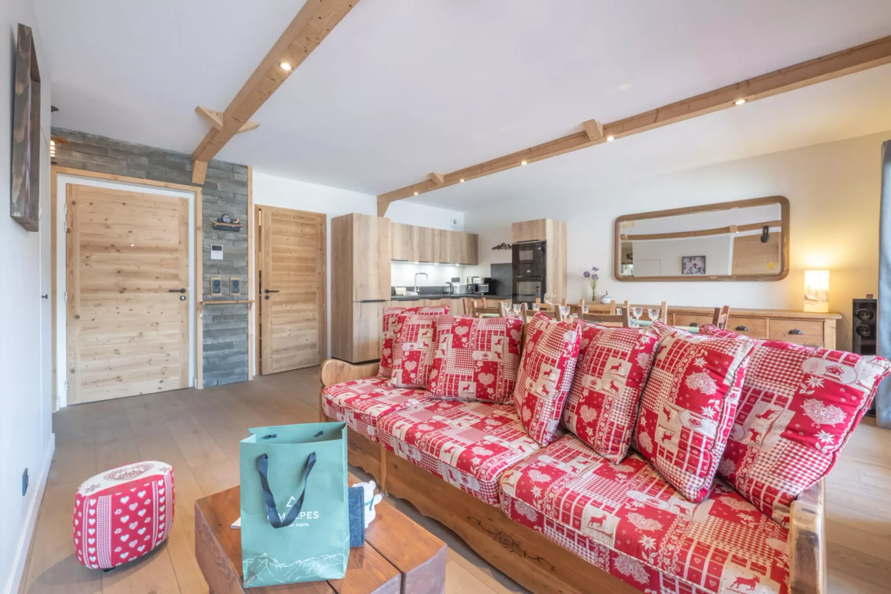 A bright living room with patterned seating and an open kitchen behind it.