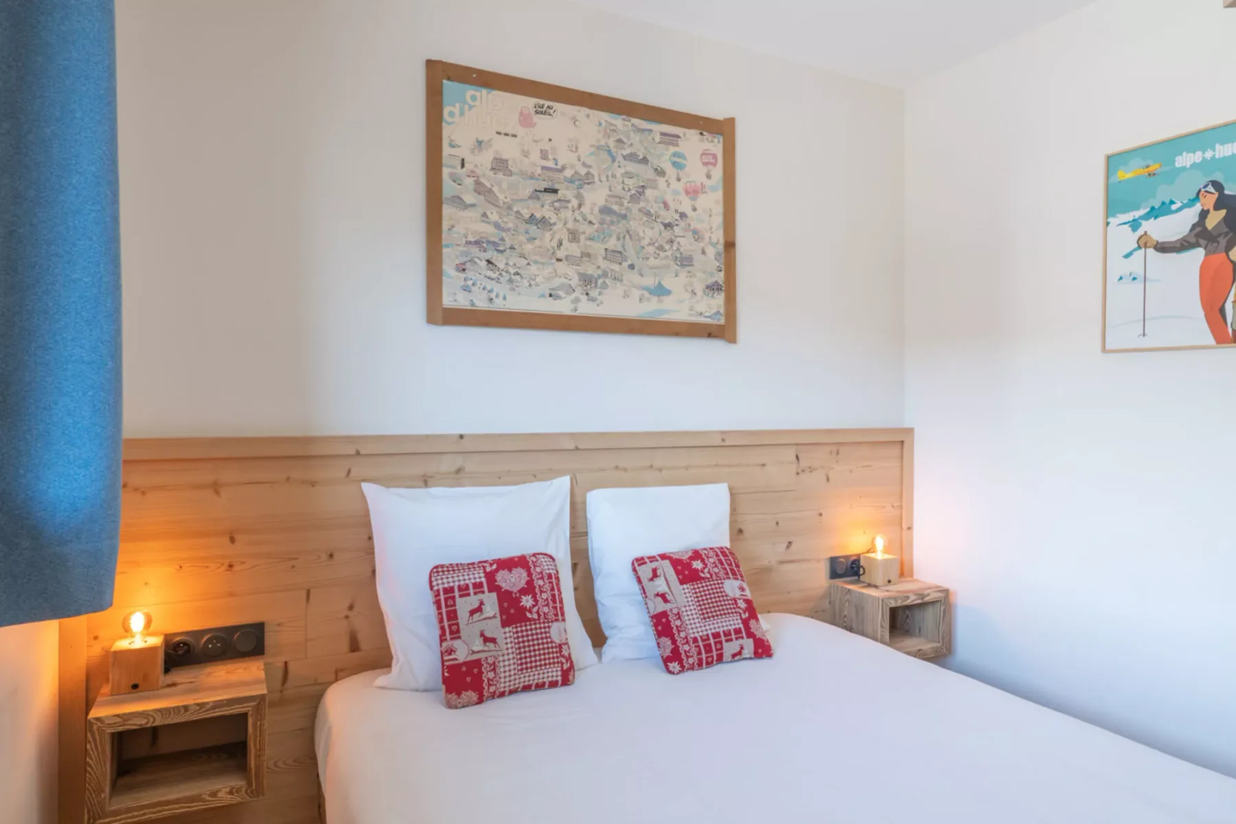 A bedroom with a white bed, patterned cushions, and framed artwork.