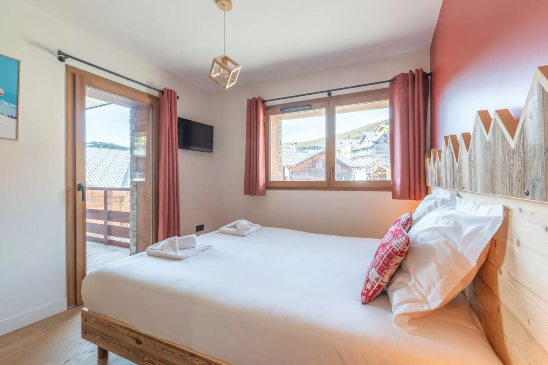 A bedroom with a bed beside a window and a glass door opening onto a balcony.