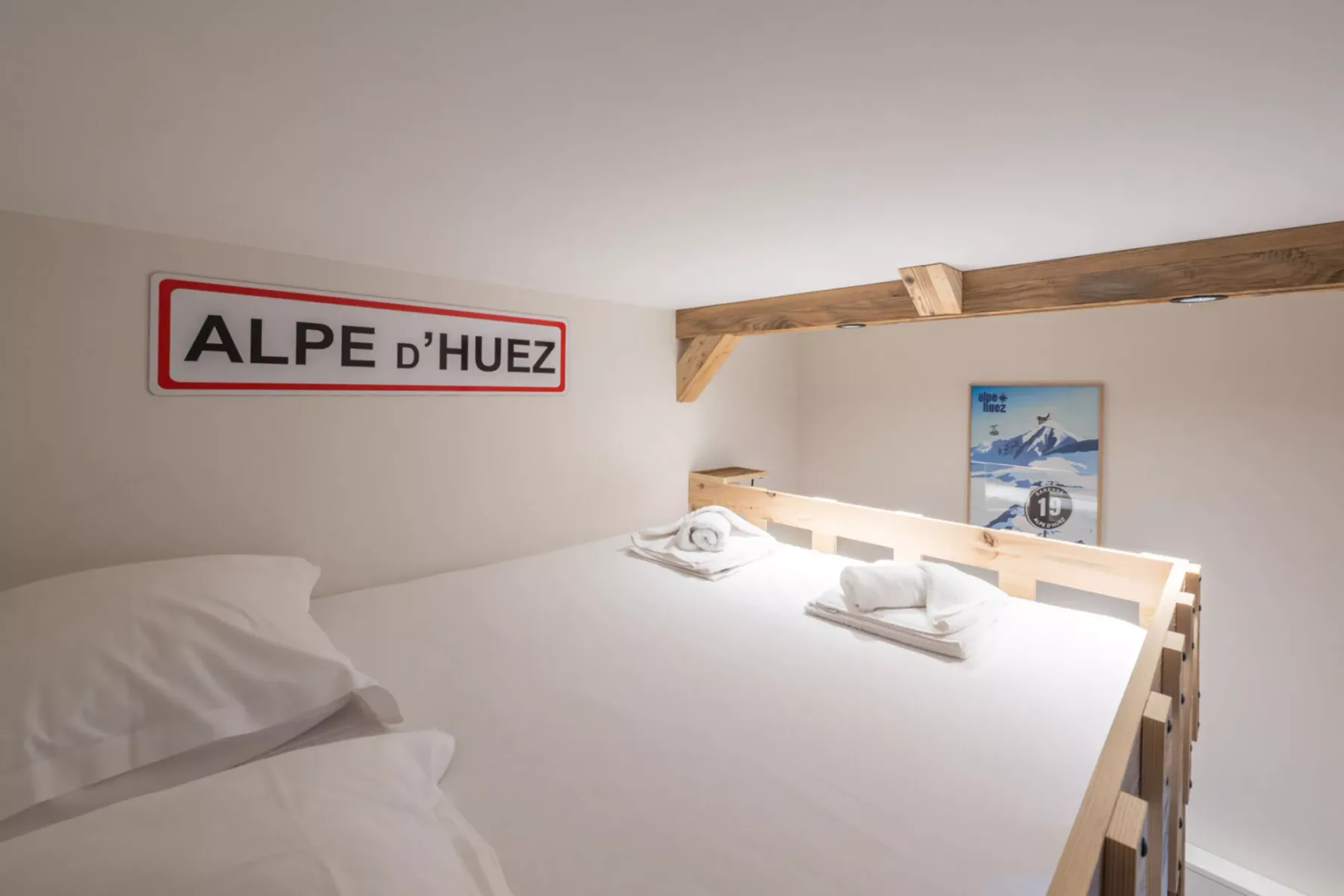 A compact sleeping area with white bedding and a wall sign.