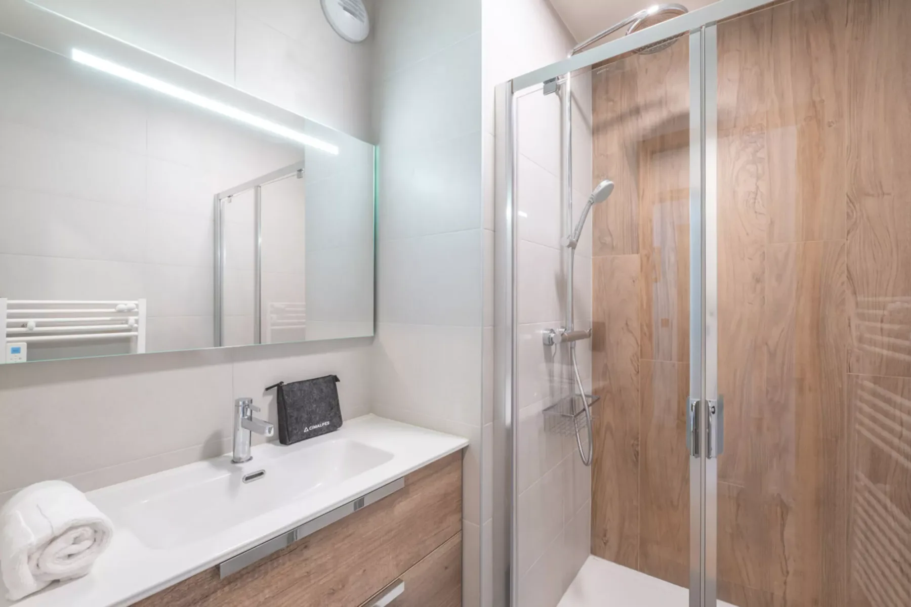 A bright bathroom with a sink and a glass-enclosed shower.