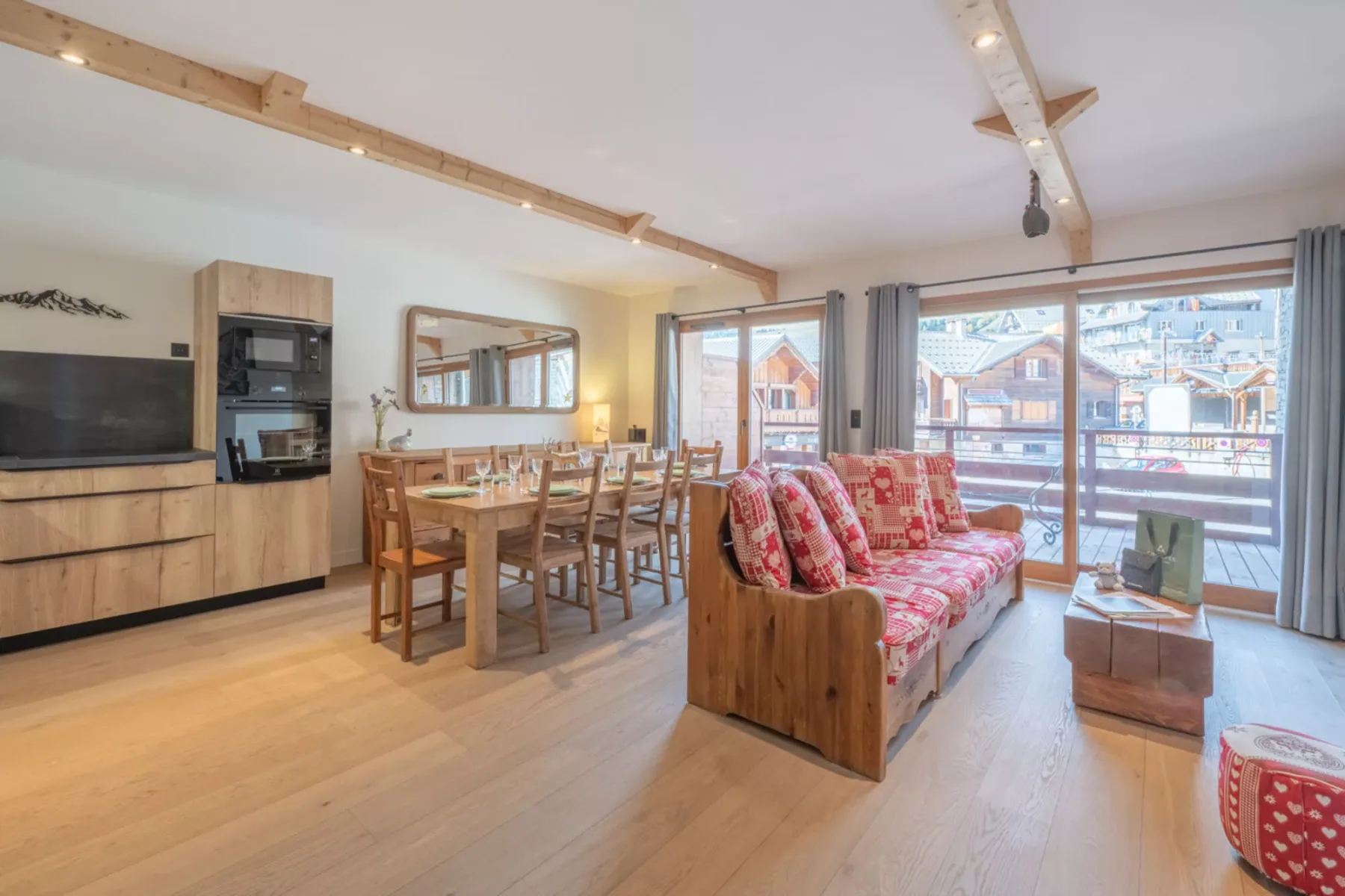 A bright open-plan living and dining area with a wooden table and patterned seating.