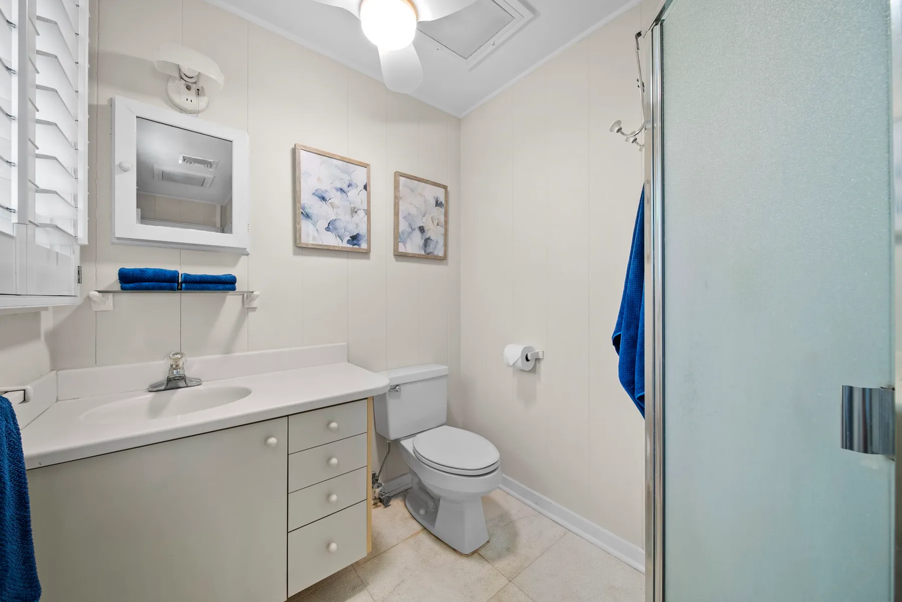 Un baño luminoso con lavabo, inodoro y ducha de vidrio.