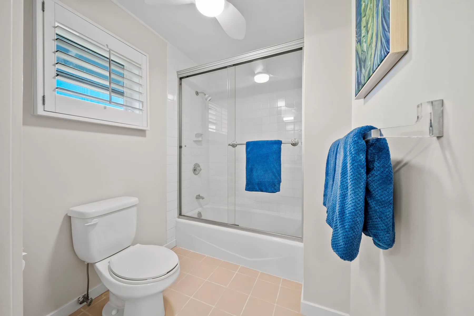 Un baño luminoso con inodoro, bañera y mampara de ducha de vidrio.