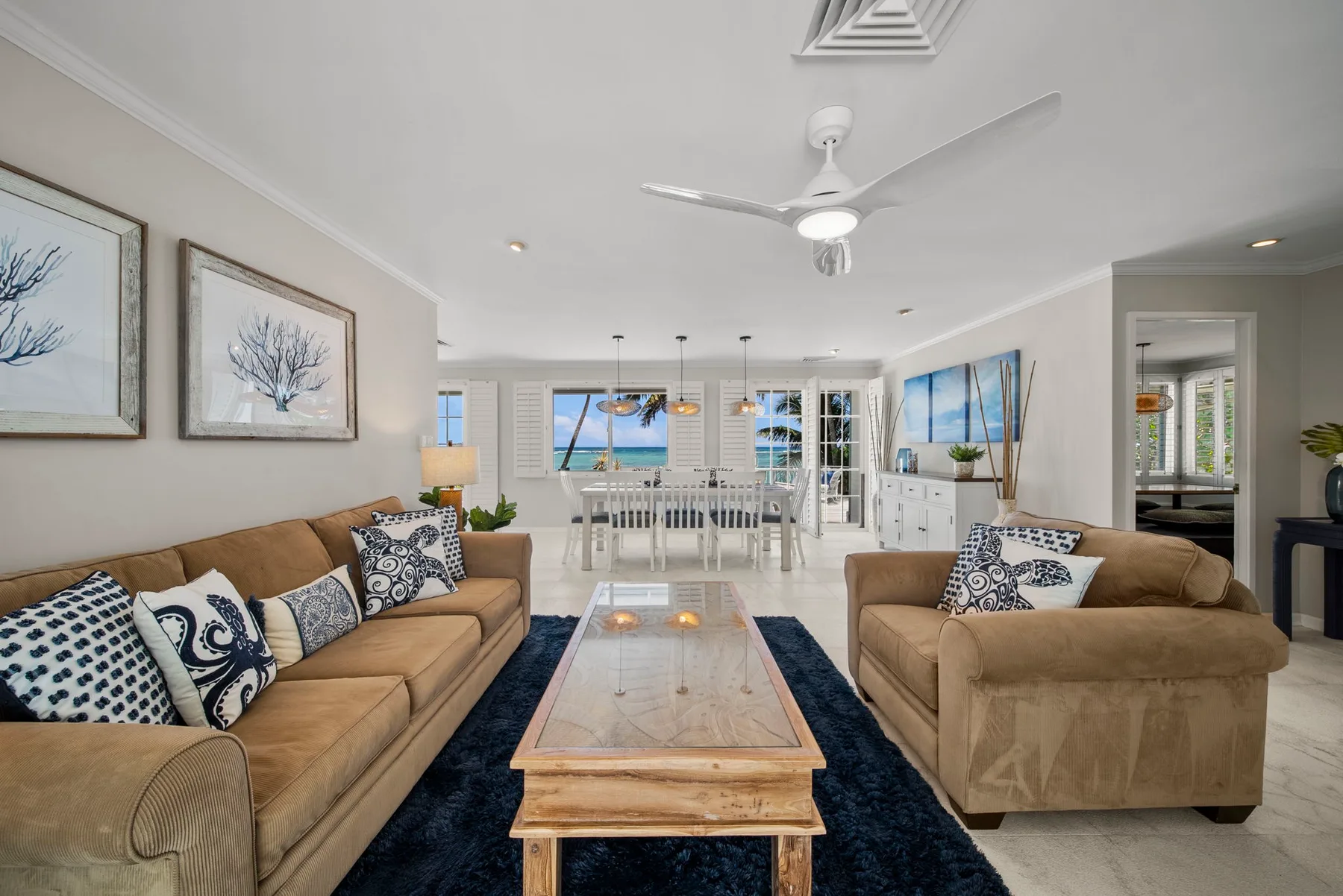 A bright living room with seating, a coffee table, and a dining area by the windows.