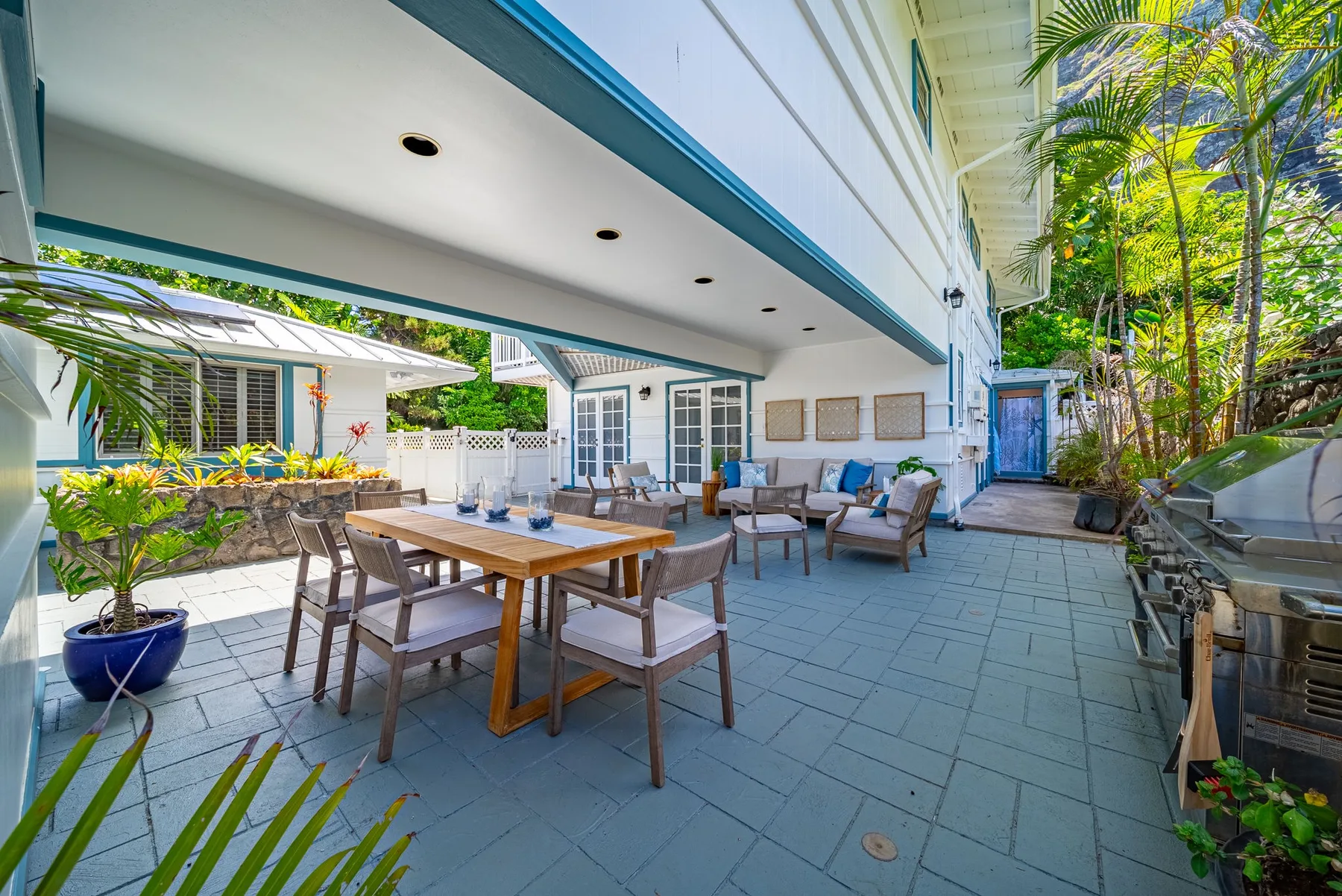 Un patio exterior con una mesa de comedor y asientos junto a un edificio blanco.