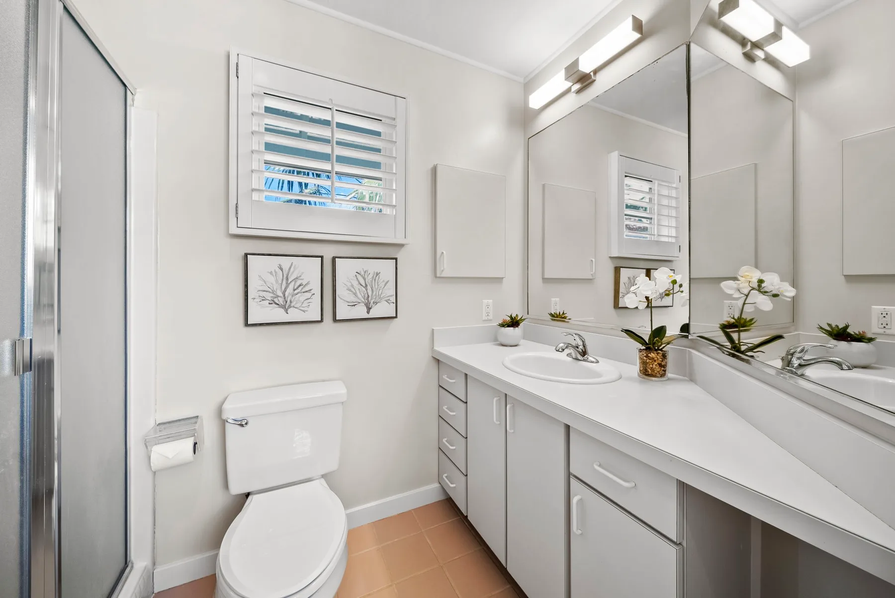 Un baño luminoso con inodoro, tocador largo y un espejo grande.