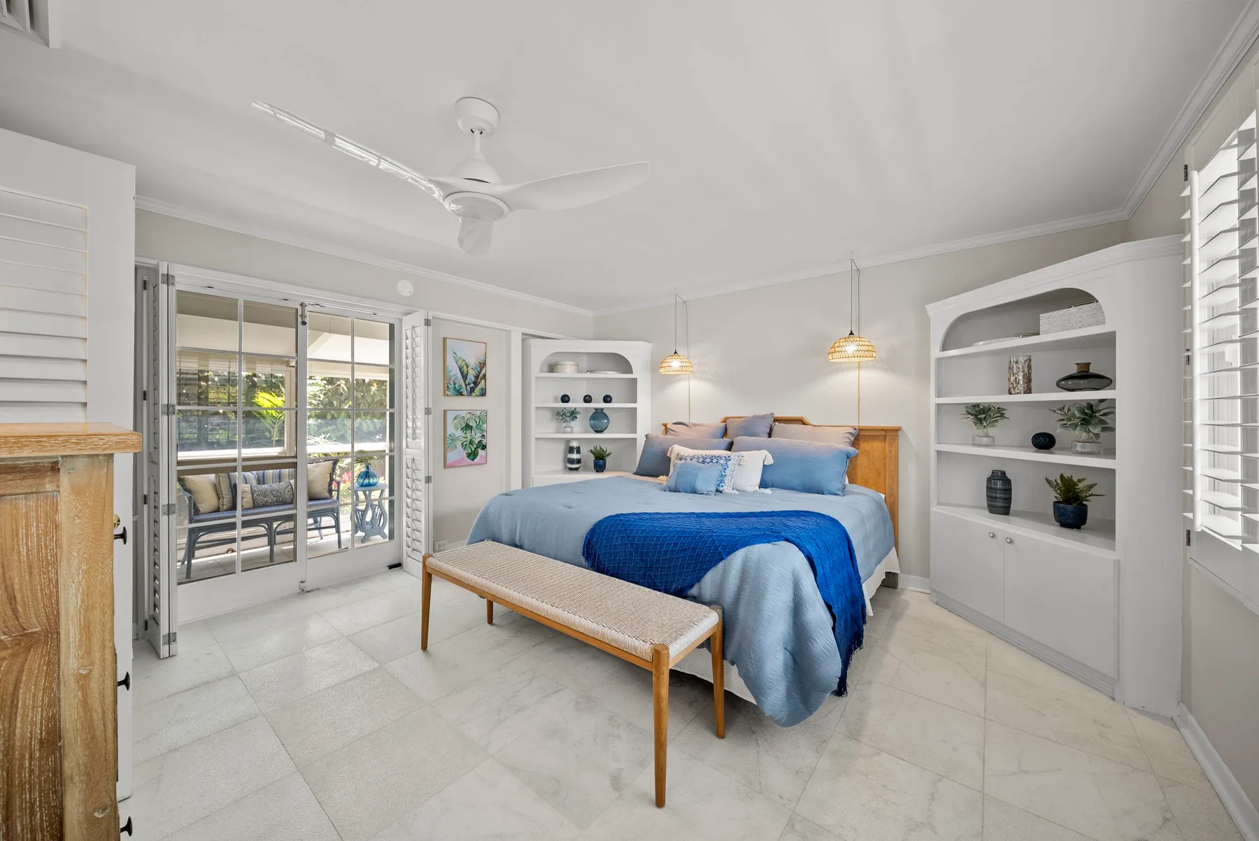 Un dormitorio luminoso con cama, estantes empotrados y puertas corredizas de vidrio.