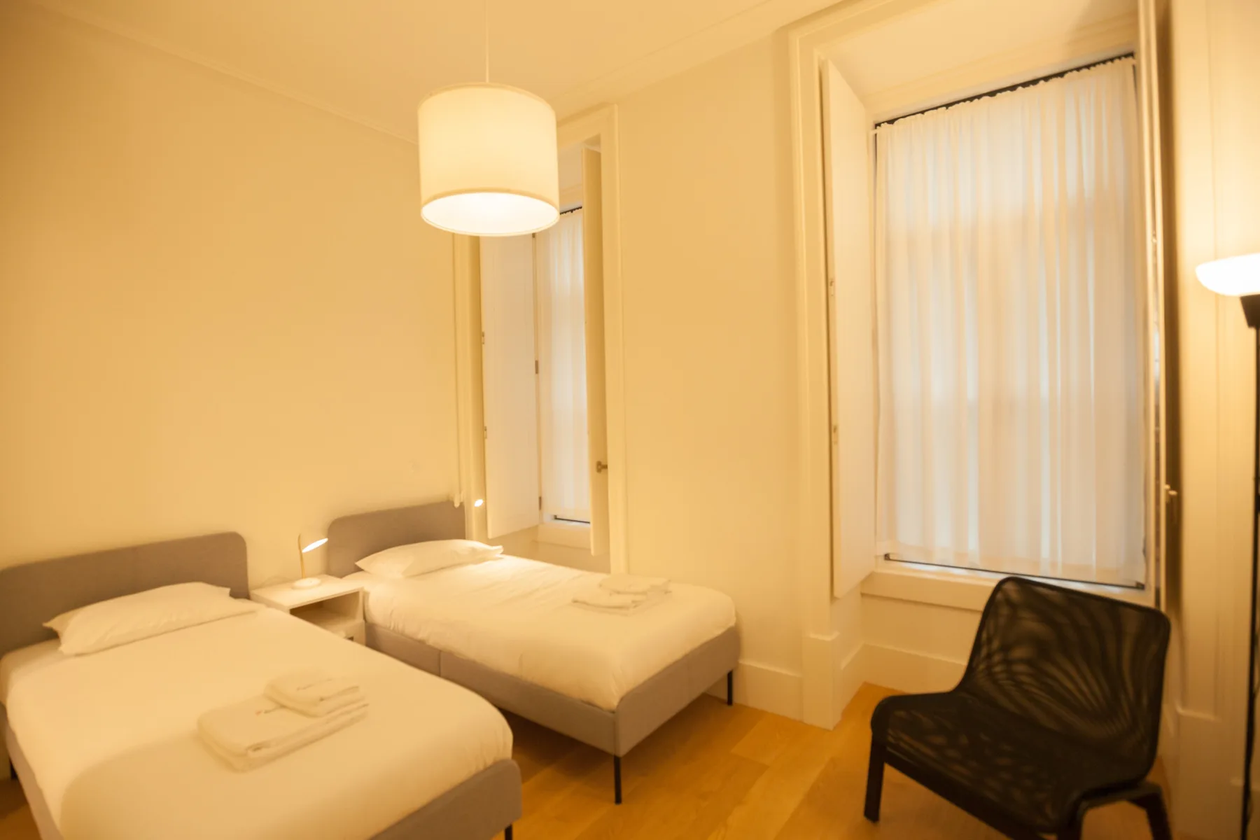 Un dormitorio con dos camas, mesillas y una ventana con persianas.