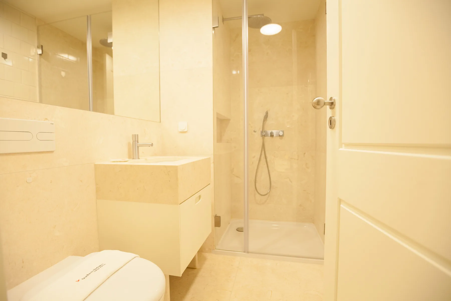 Un baño luminoso con lavabo, espejo y ducha de cristal.