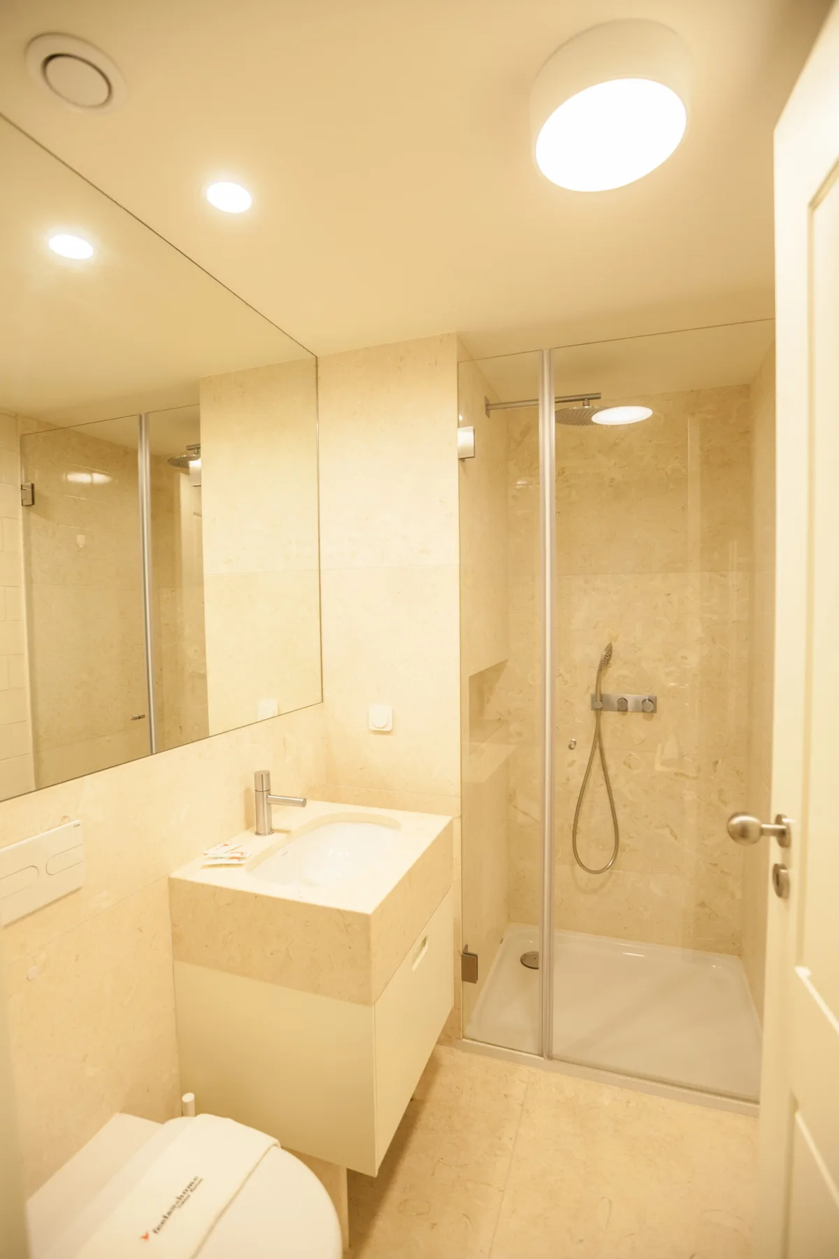 A bright bathroom with a vanity, mirror, and glass shower.