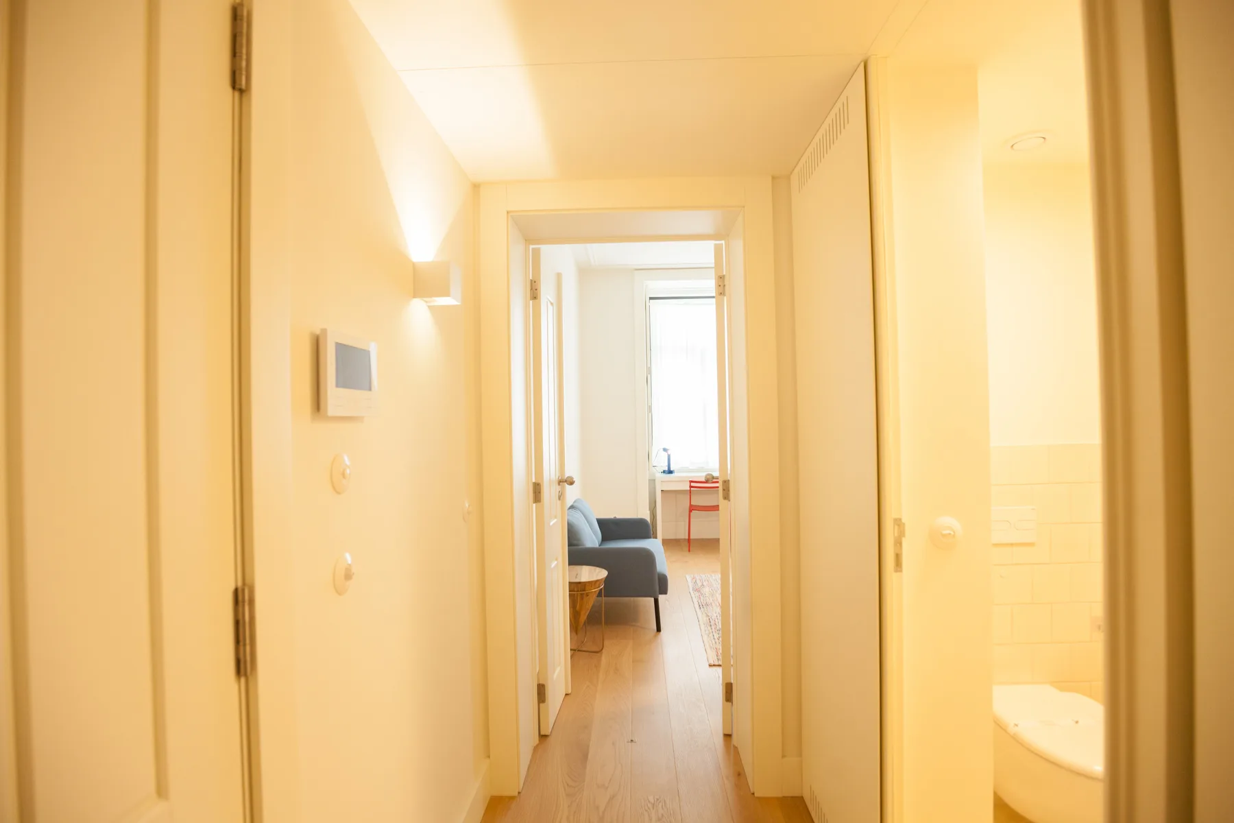 Un pasillo conduce a una zona de estar, con parte de un baño visible al lado.