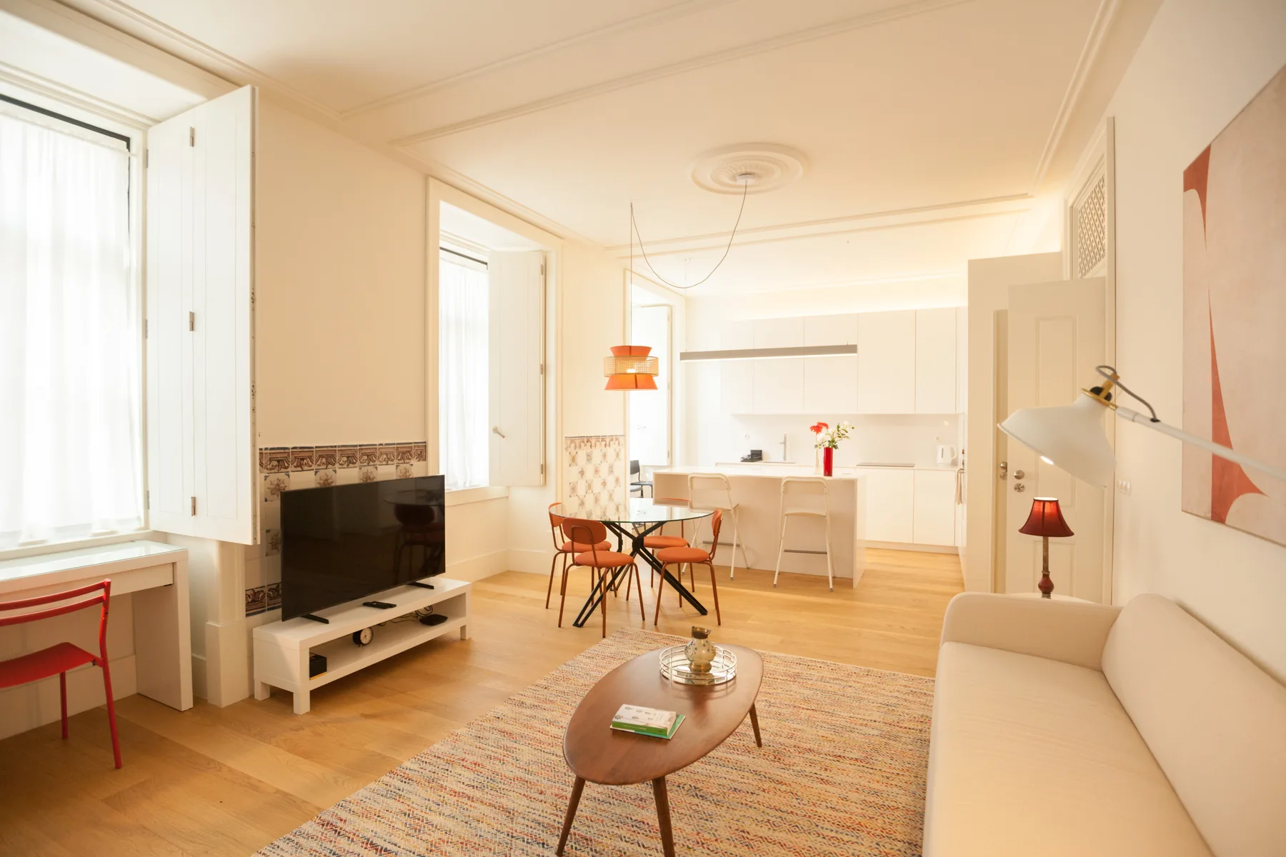Una luminosa sala de estar con asientos, un televisor y una cocina abierta.
