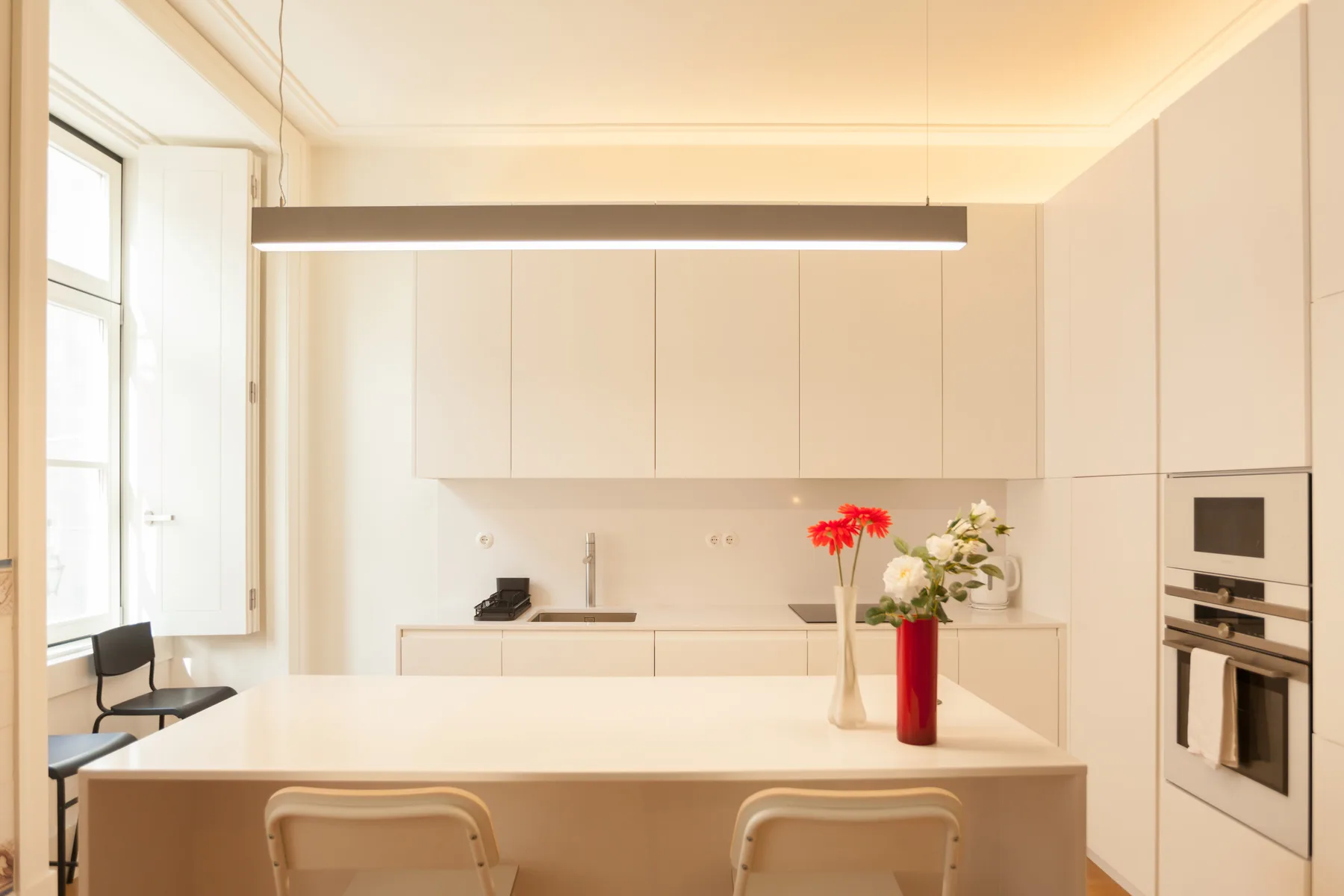 Una cocina moderna y luminosa con una barra y armarios claros.