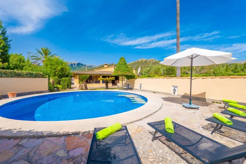 Outdoor pool patio with lounge chairs and a large white umbrella.