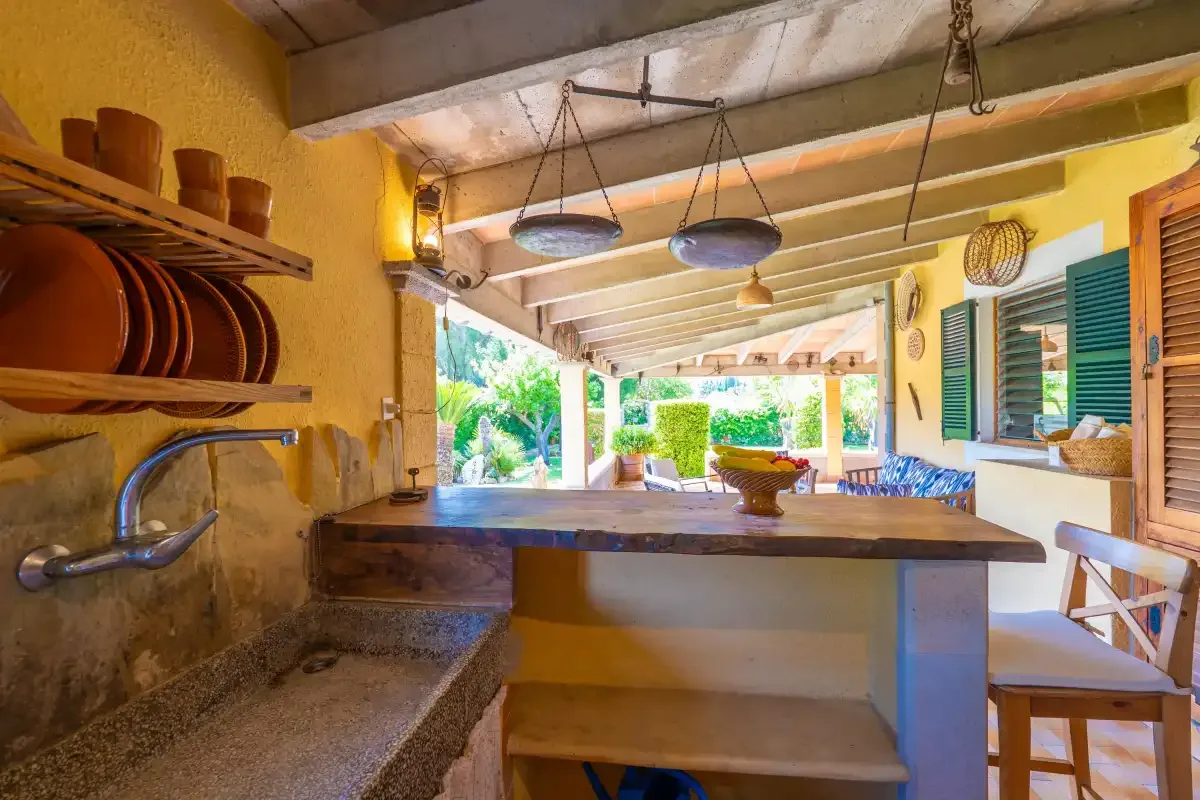 A covered outdoor kitchen opens onto a bright patio with seating.