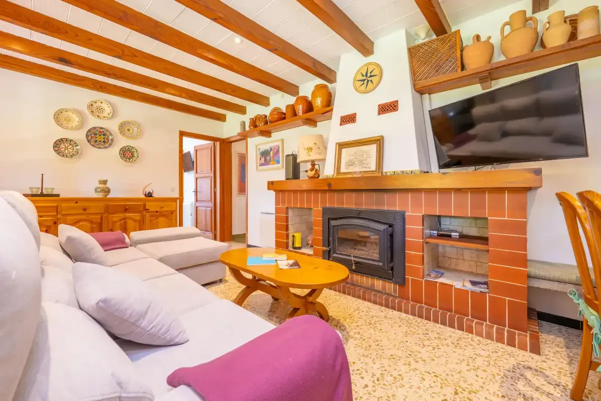 A living room with seating, a television, and a tiled fireplace.