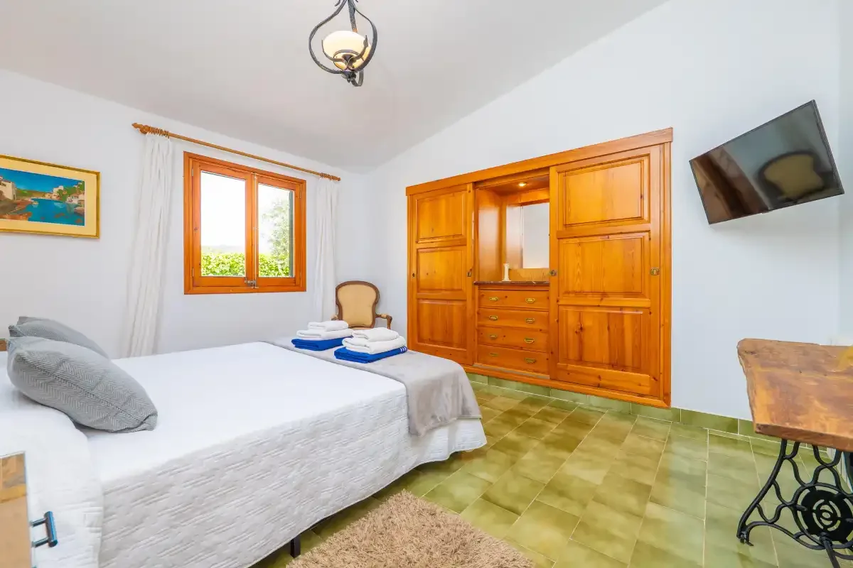 A bedroom with a bed, wooden wardrobe, and window.