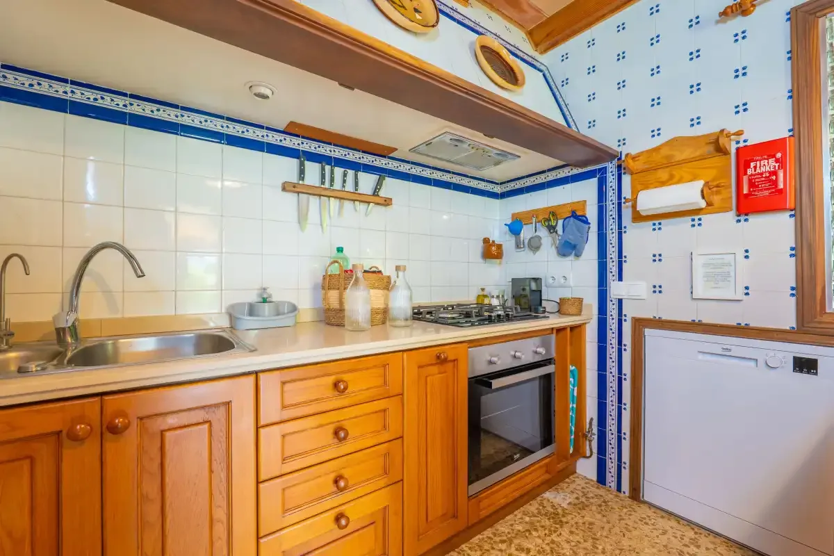 A tiled kitchen with wooden cabinets, a sink, and a built-in oven.
