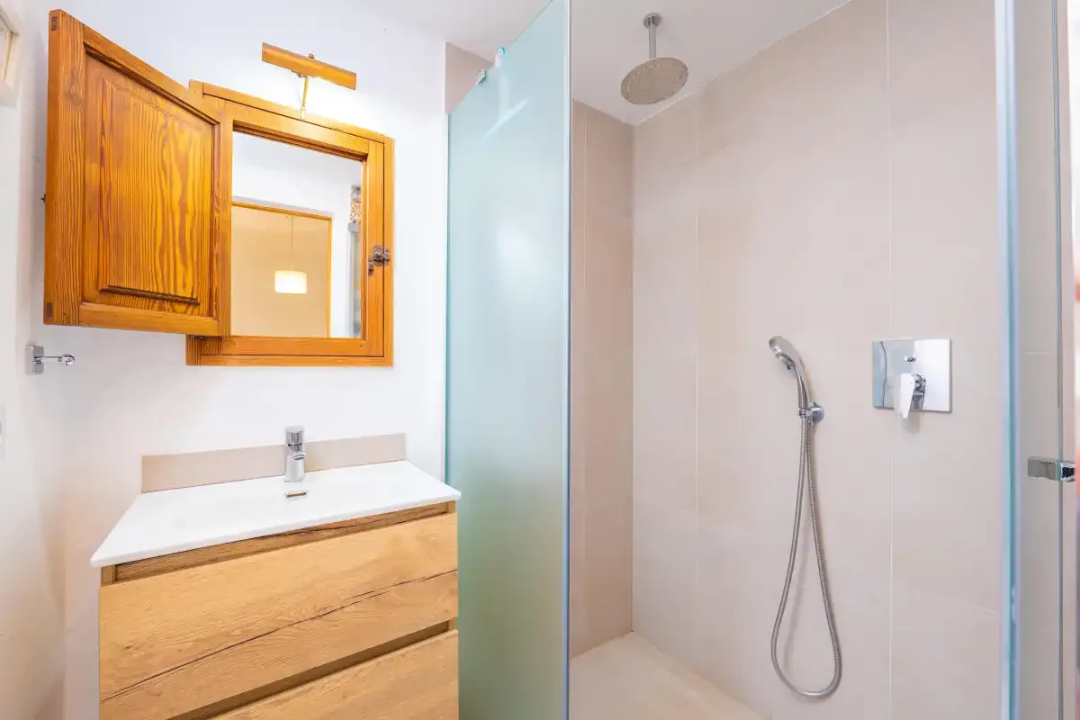 A bathroom with a wooden vanity beside a walk-in shower.