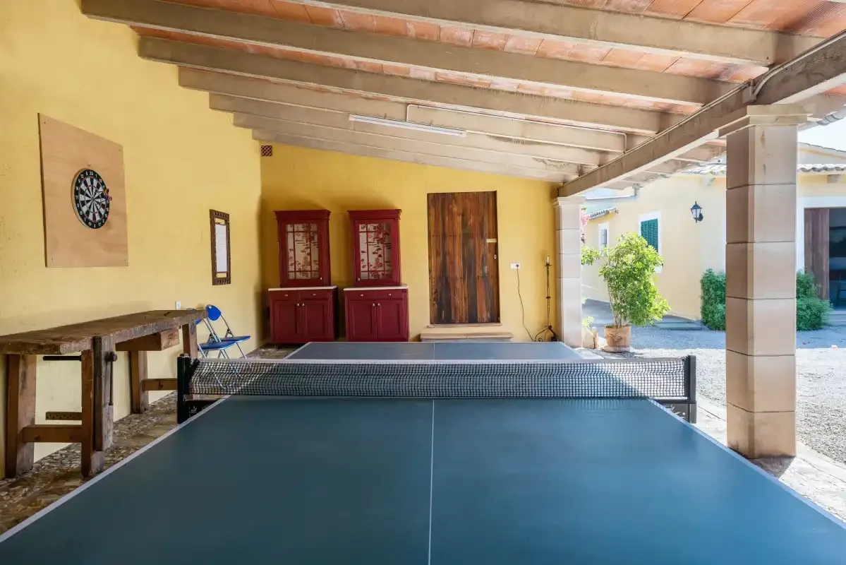 A covered recreation area features a table tennis table and dartboard.
