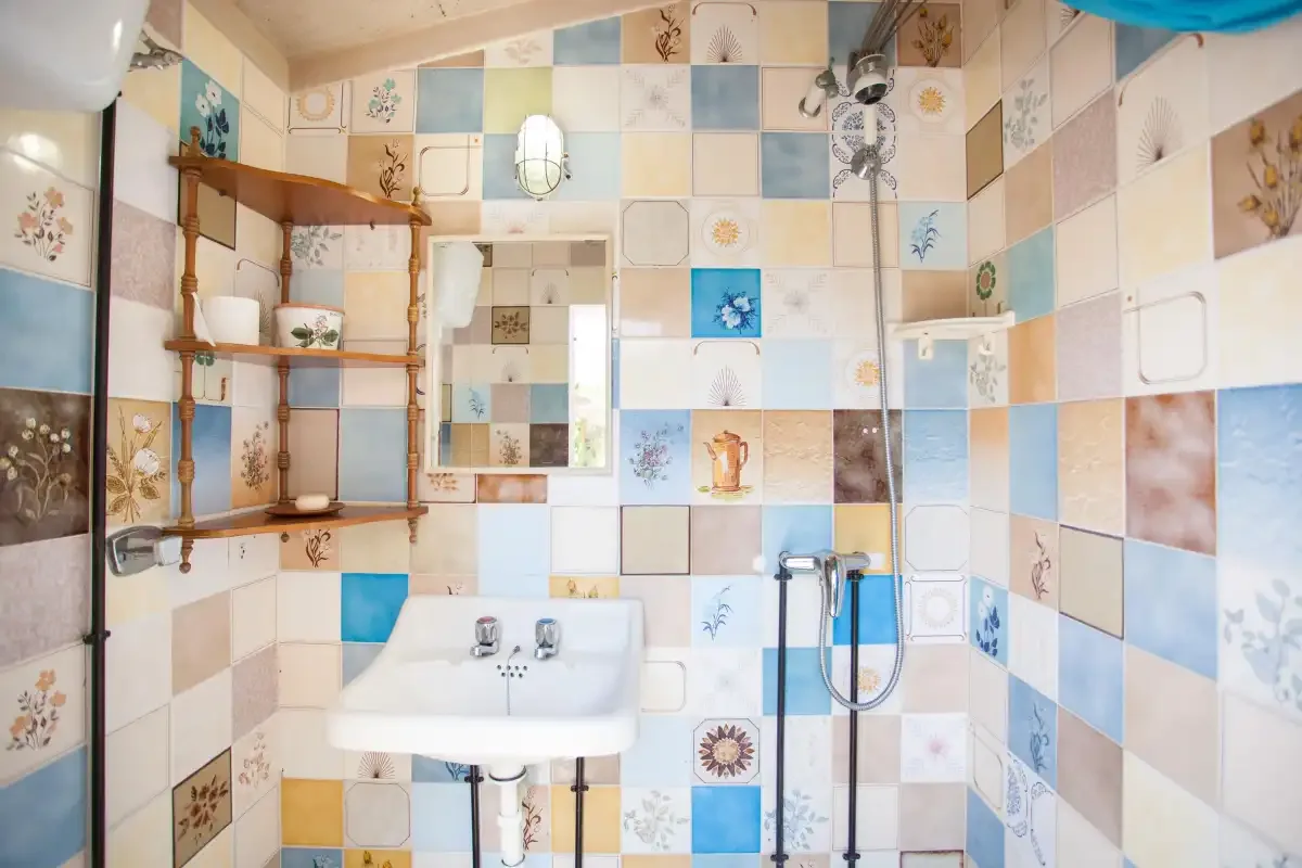 A bathroom with a wall-mounted sink and tiled walls.