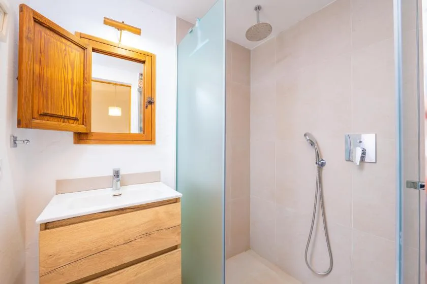 A bathroom with a wood vanity beside a glass-enclosed shower.