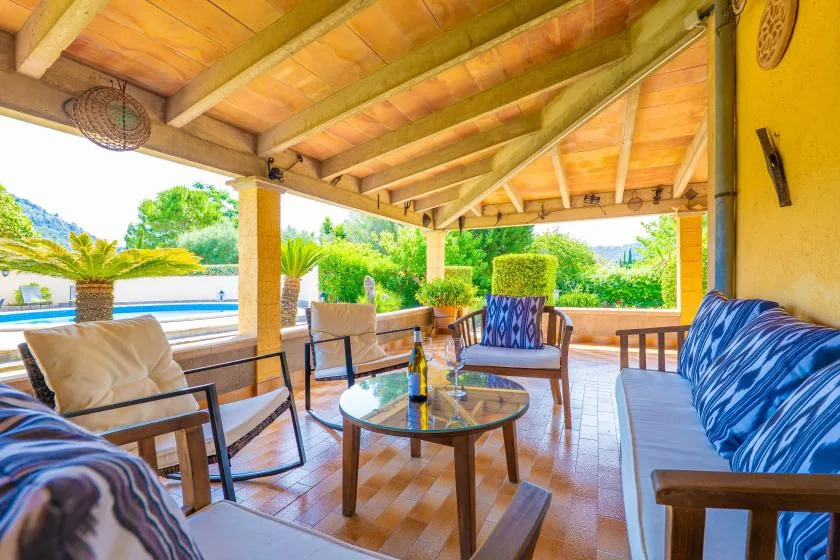 A covered outdoor seating area with cushioned chairs and a glass coffee table.