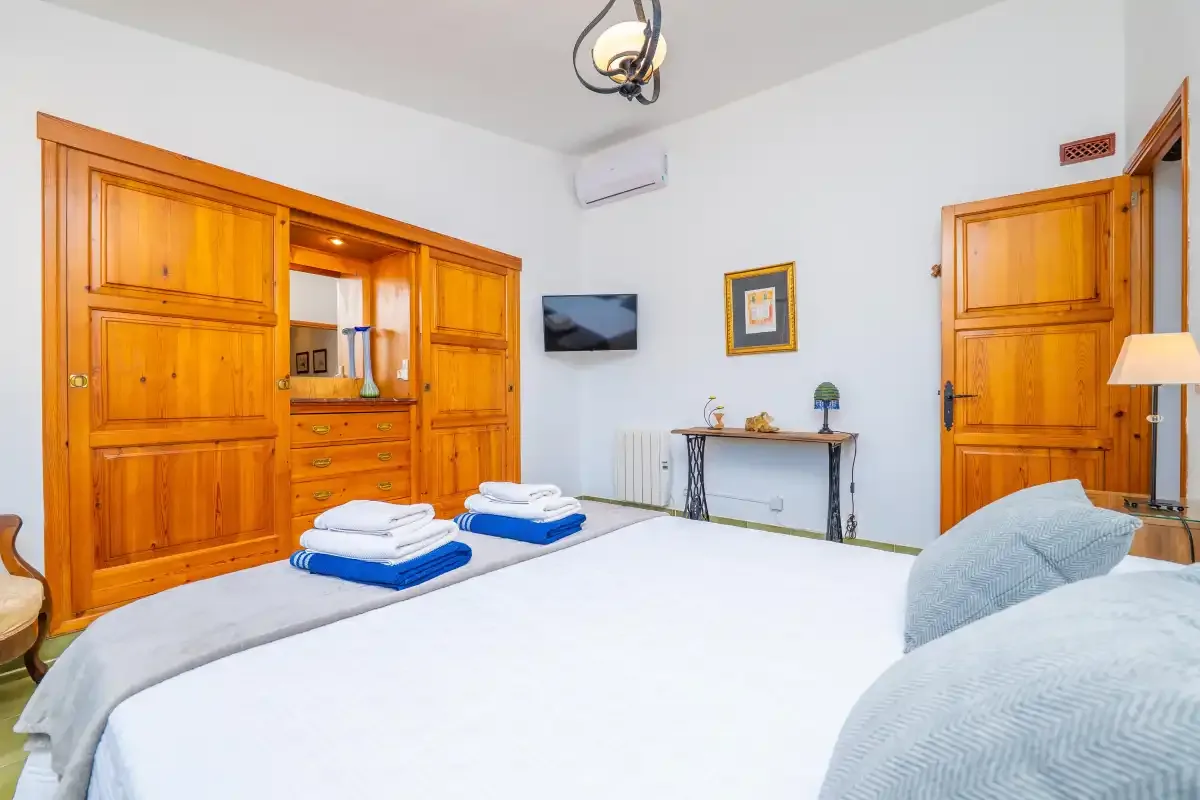A bedroom with a large bed and wooden wardrobes.