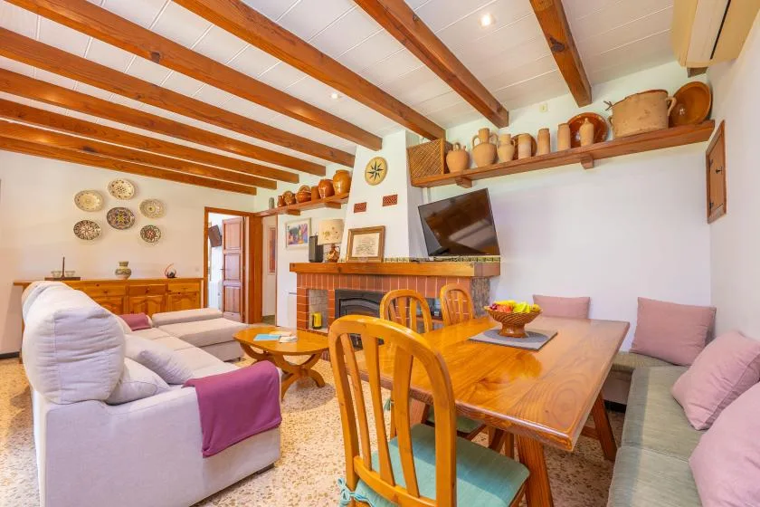 A dining and living room with wooden furnishings, seating, and exposed ceiling beams.