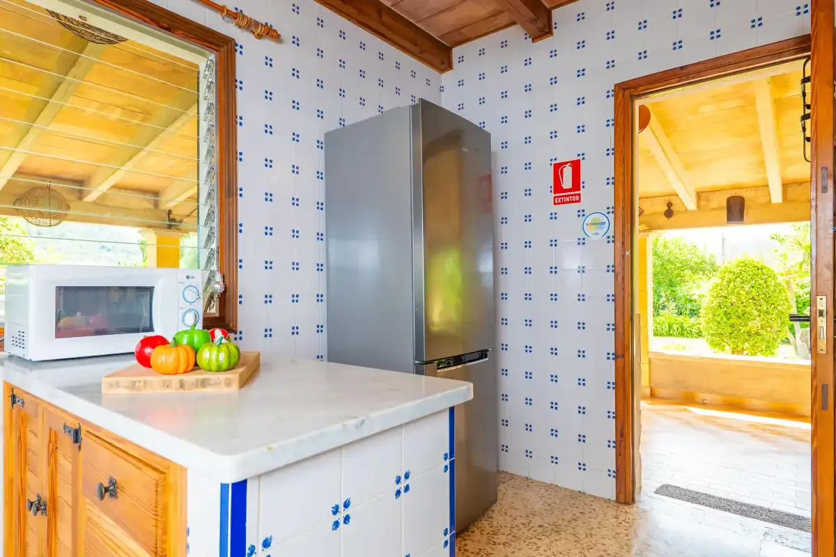 A kitchen with a countertop, microwave, and refrigerator beside an open doorway.
