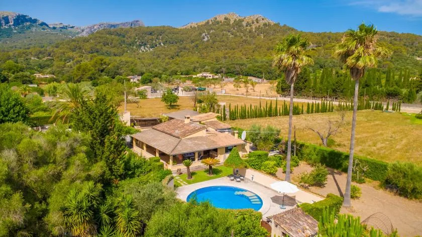 A landscaped property with a swimming pool sits amid green hills and trees.
