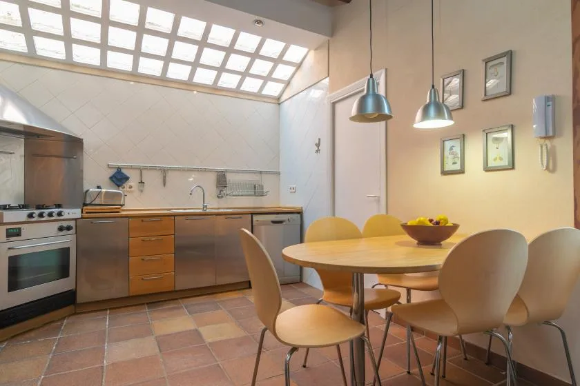 A kitchen and dining area with wooden cabinets, a table, and chairs.